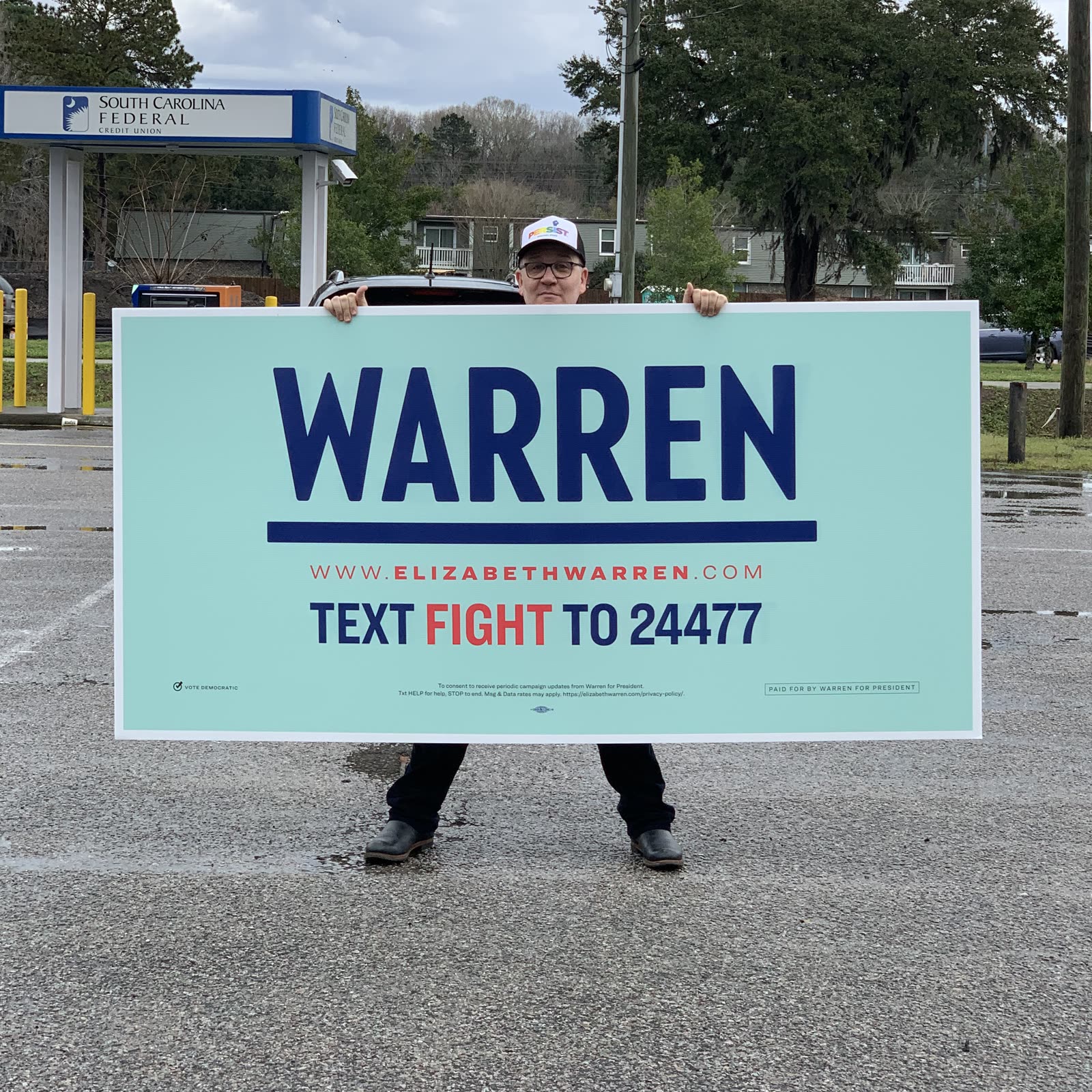 Blue Moreno peeking over an oversized Warren campaign sign