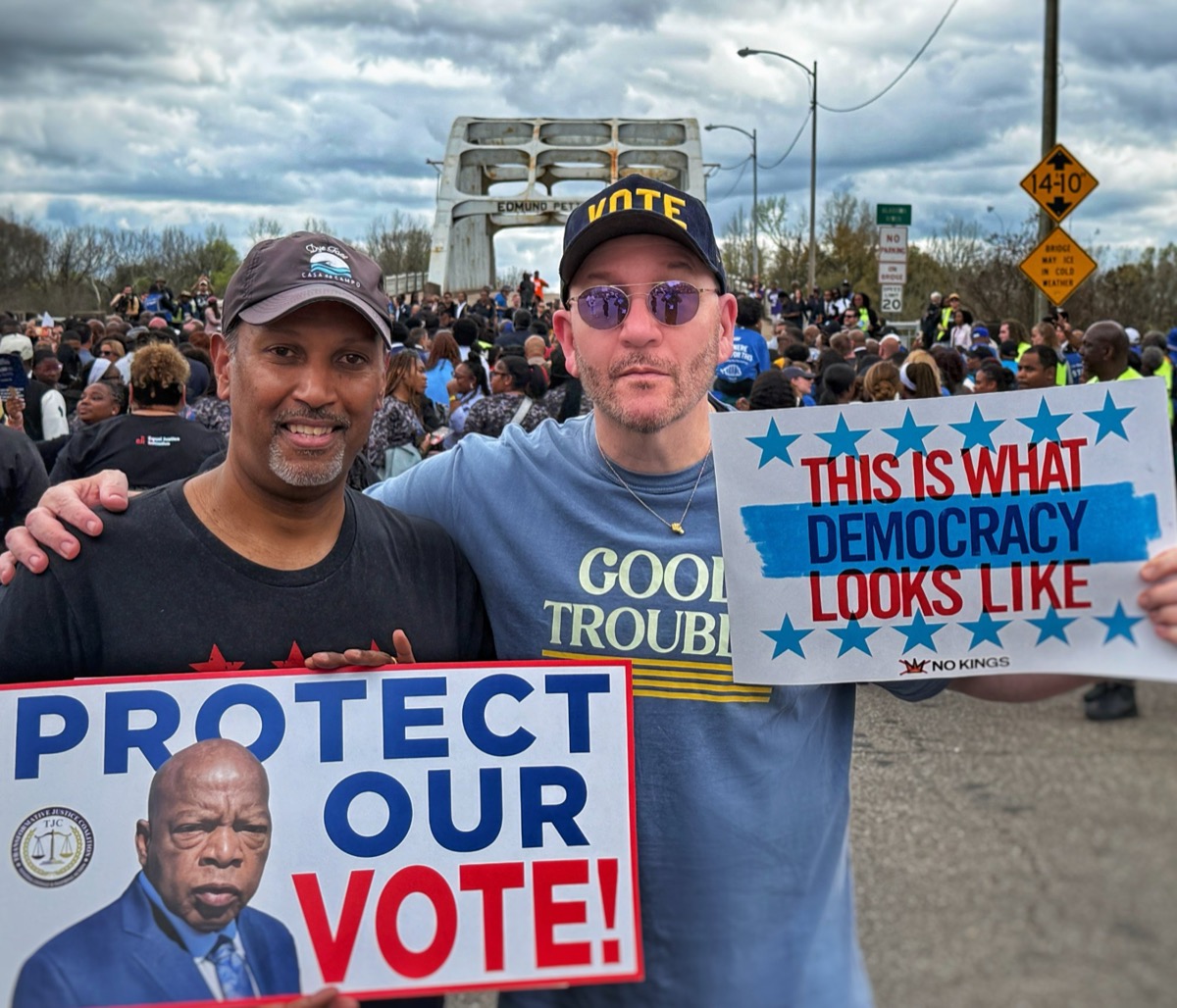 Blue Moreno and a volunteer holding Protect Our Vote and This Is What Democracy Looks Like signs at a rally