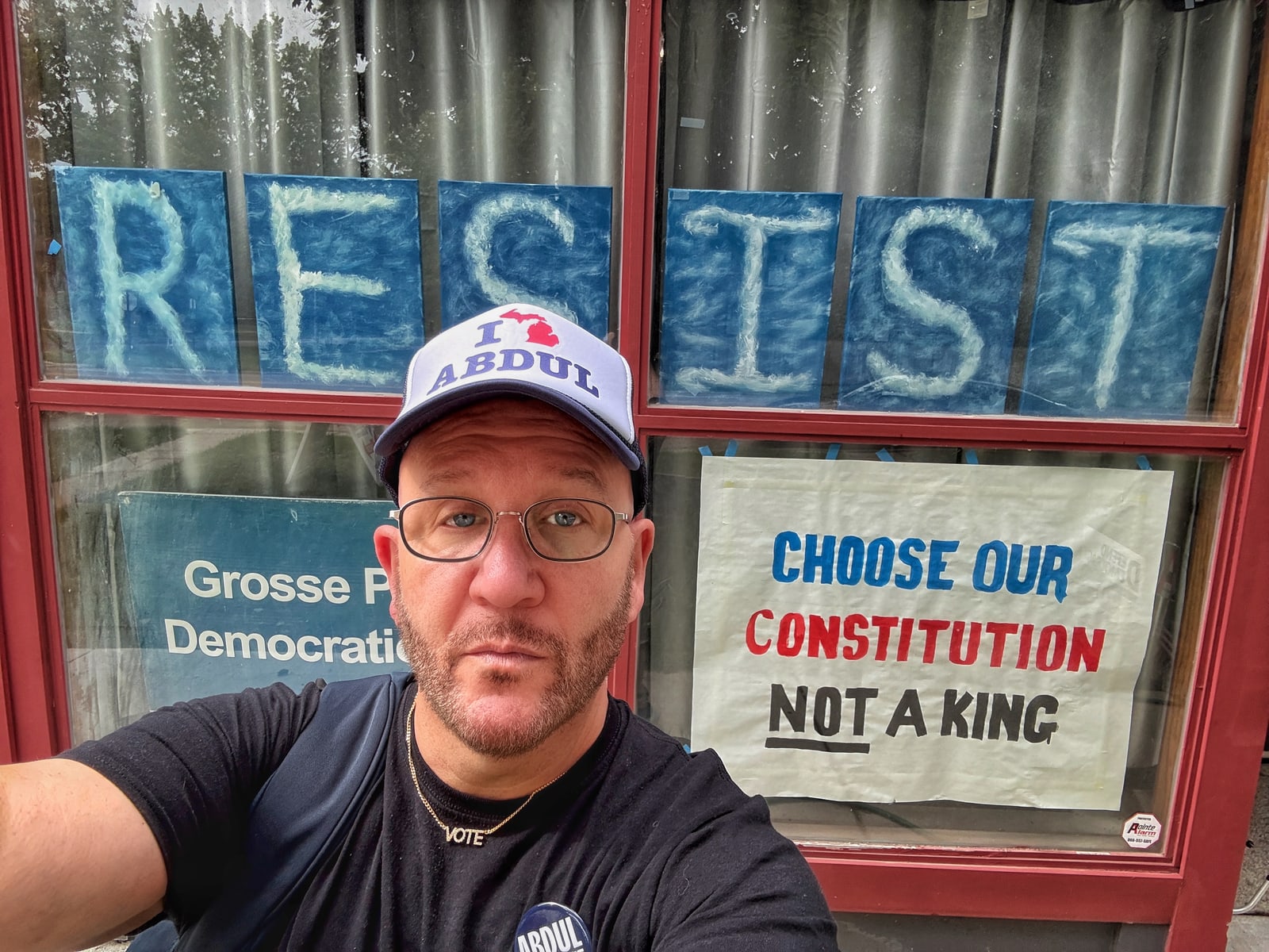 Blue Moreno in an I Heart Abdul hat outside the Grosse Pointe Democratic office, with RESIST signs in the window