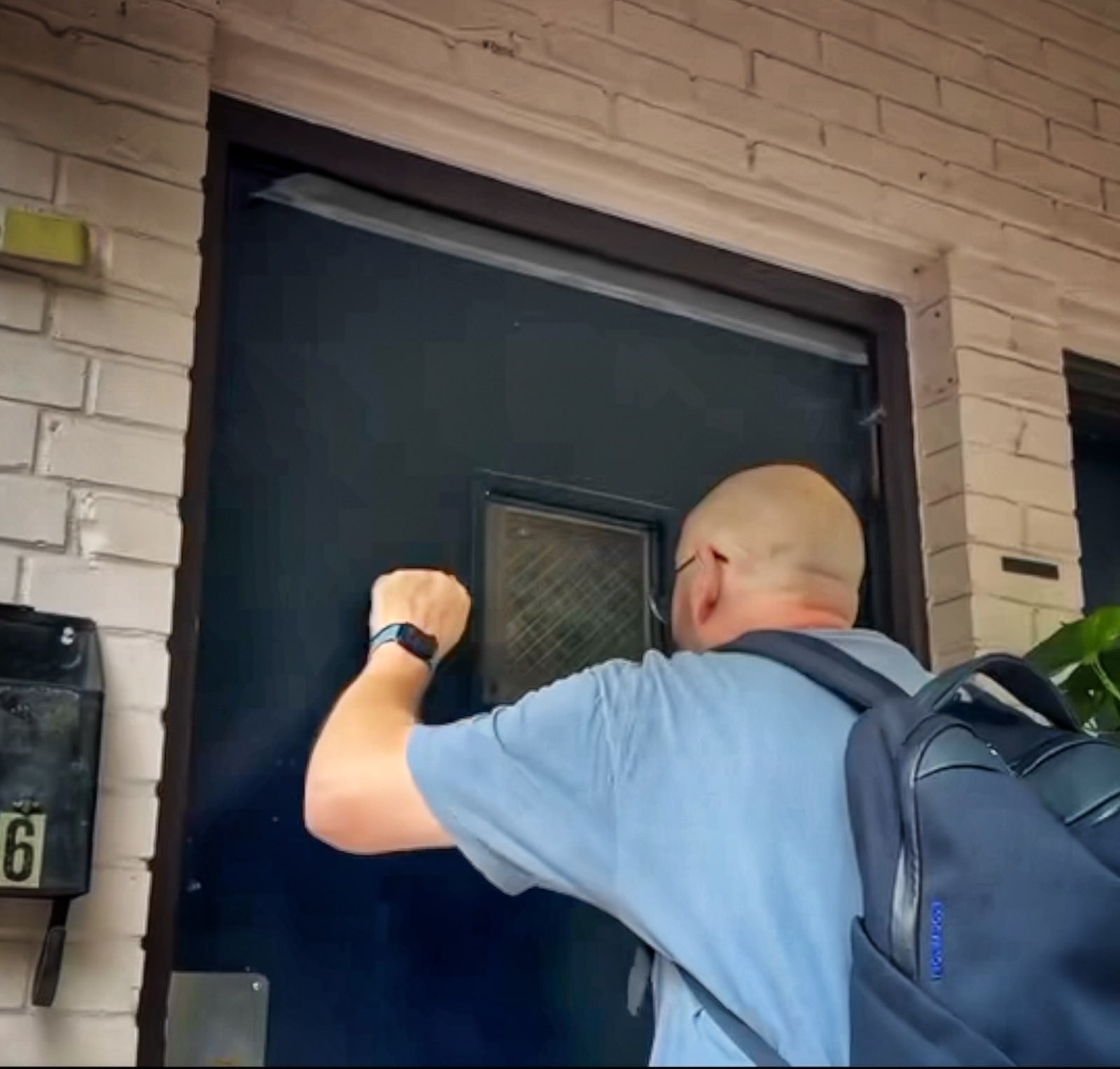 Blue Moreno wearing a backpack and knocking on a dark blue door in Georgia