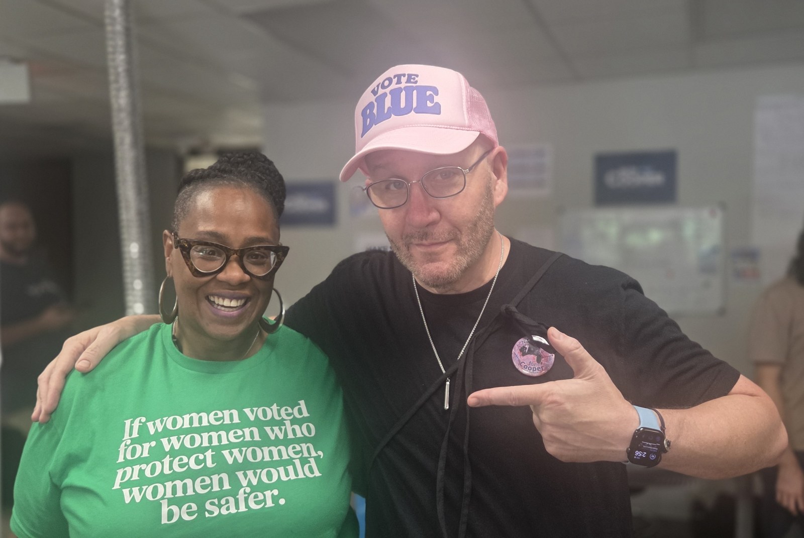 Blue Moreno in a pink Vote Blue hat posing with a woman wearing a green shirt in North Carolina