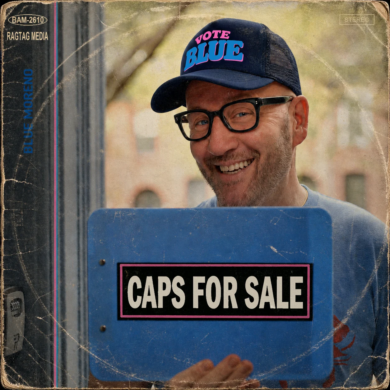 Caps for Sale album cover. Blue Moreno smiles over a blue clipboard while wearing a navy Vote Blue trucker hat. The weathered sleeve includes BAM-2610 and Ragtag Media catalog marks.