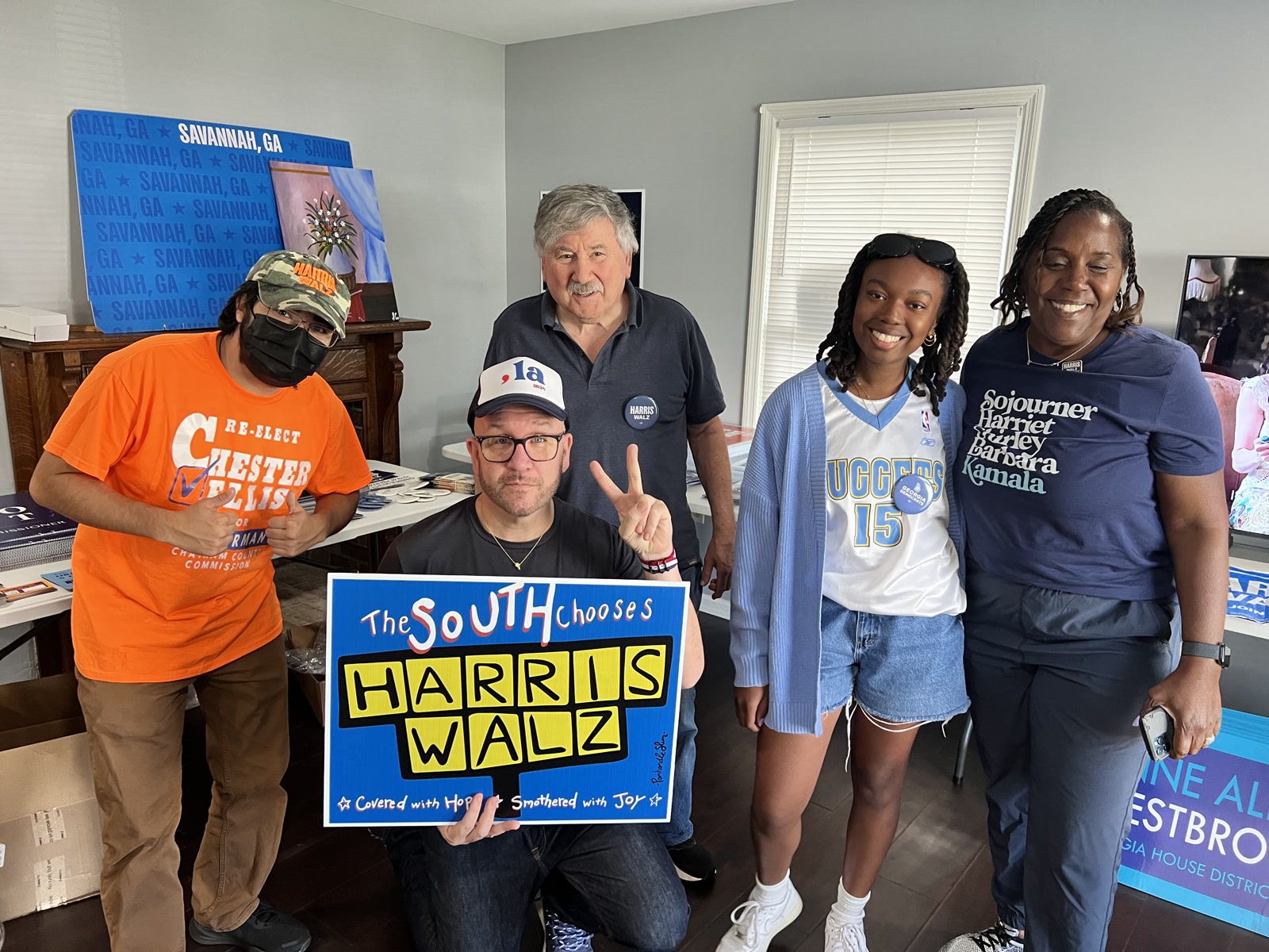 Blue Moreno and four volunteers pose with a hand-painted Harris Walz sign in a Savannah field office.